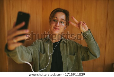 European girl using a mobile phone communicates with friends in an online chat. a smiling girl with glasses communicates in an online chat via video communication. vintage photo processing