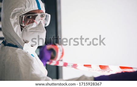 Doctor seals off contaminated area with barrier tape during coronavirus (Coivd-19) epidemic in a clinic at the  intensive care unit Royalty-Free Stock Photo #1715928367