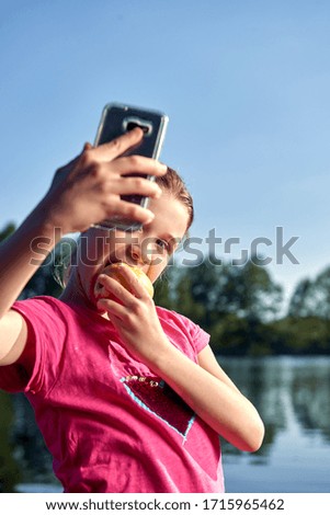 Girl plays with her mobile phone at the lake and makes a selfi and enjoys your holidays
