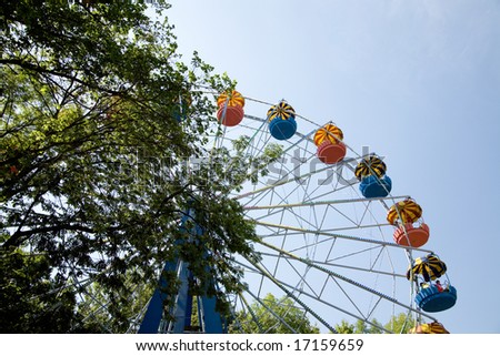 Popular attraction in park - a Ferris wheel on a background of the cloudy blue sky