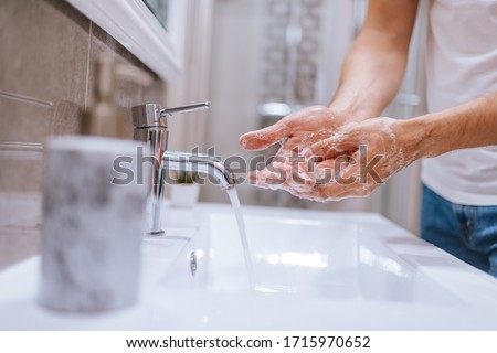 Close up of caucasian man washes his hands in the bathroom. COVID - 19 prevention Royalty-Free Stock Photo #1715970652