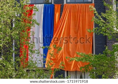 National holiday King’s Day or Koningsdag in Dutch, Due to Coronavirus disease (COVID-19) scourge, Celebrations will not take place this year, Netherlands flag and orange flag hanging outside building
