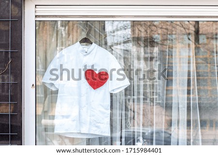 The part of white medical suit with print red heart is in the window in Amsterdam. The sign of thanks to medical workers