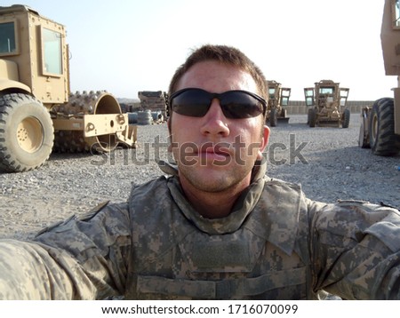 Young soldier sits with heavy equipment machines, tools of the job he does for the army