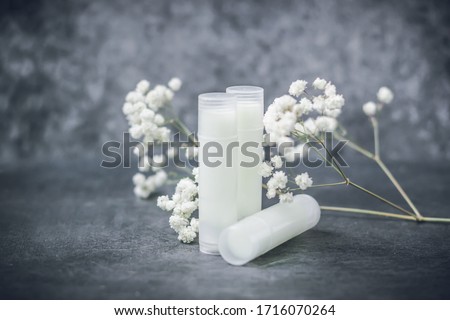 lip balm with flowers in a transparent tube with white contents. DIY lipstick made from natural eco-friendly ingredients. hand made on a gray background