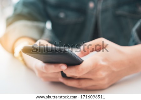 Woman hand using smartphone to do work business, social network, communication in public cafe work space area.
