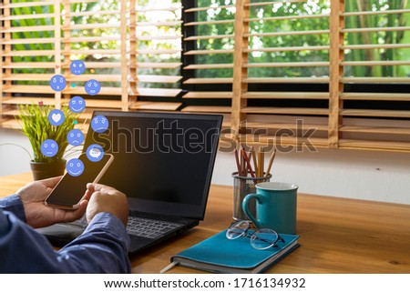 Man hand using a social media marketing concept on mobile phone with notification icons of like, message, comment and star above mobile phone screen.