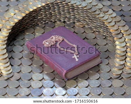a gold cross on a chain lies in a religious book surrounded by coins the Russian ruble