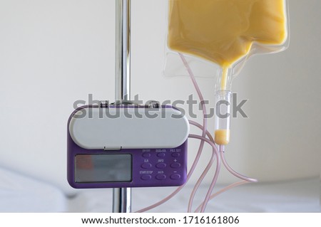 Feeding Pump medical device purple color to supplement nutrition liquid food to tube enteral feeding fluid set bag with clamp hanging on stand. Royalty-Free Stock Photo #1716161806