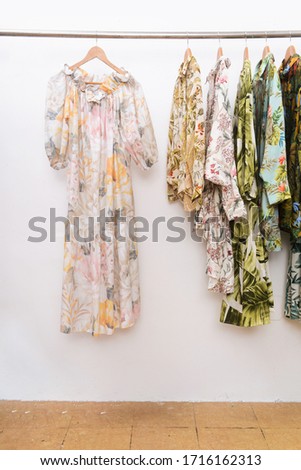 Row of women's sundress dress with a floral .palm pattern sundress, blouse ,shirts on hanger