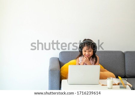 Asian girl using desktop computer for online study homeschooling during home quarantine. homeschooling, online study, home quarantine, online learning, corona virus or education technology concept Royalty-Free Stock Photo #1716239614