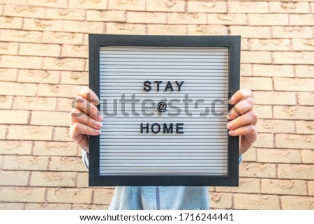 Hands holding 'Stay at home' sign board with frame and typography letters for prevention of Corona Virus COVID19 epidemic