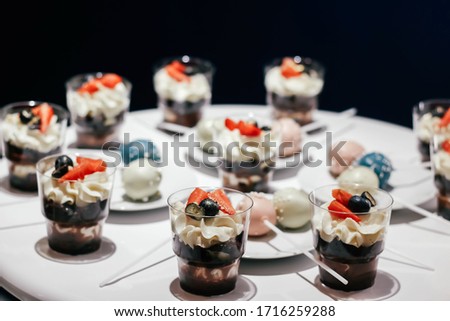 Desserts with whipped cream and strawberries on a white table. Glamorous style