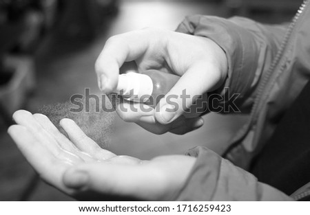 
Antiseptic spray. Preventive measures in the context of the coronavirus pandemic. The guy is spraying on his hands. Black and white photo. Close-up. Hygiene and health concept.