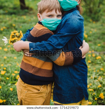 Boy and girl wearing a medical mask, flowers on the background. Children in a protective mask. Warning of the dangers and safety quarantine measures against COVID-19. Coronavirus pandemic.