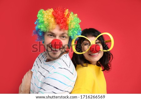 Couple with funny accessories on red background. April fool's day Royalty-Free Stock Photo #1716266569