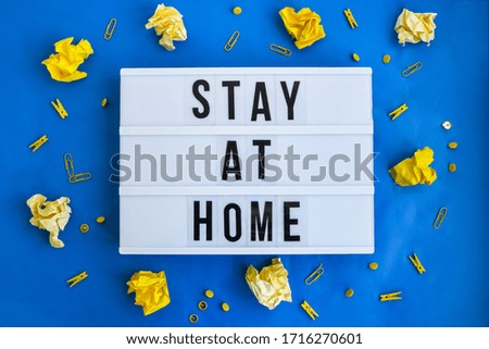 lightbox with text STAY AT HOME in front blue background, copy space, banner for freelance coronavirus covid-19 quarantine crumpled yellow papers, business planning and brainstorming