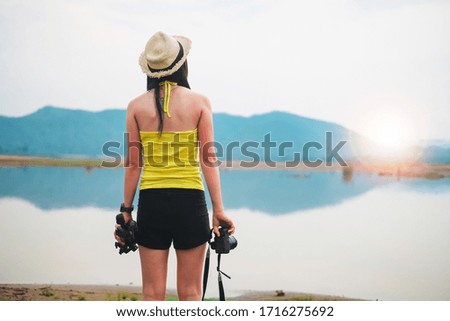 woman photographer take camera and tripod alone near the lake on vacation. 