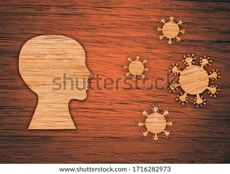 The silhouette of a human head, the virus on a brown wooden background. The epidemic of the coronavirus, pandemic.
