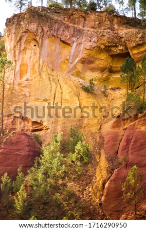 Vertical picture of ochre Trail in Roussillon, Sentier des Ocres, hiking path in natural colorful area of red and yellow cliffs in disused ocher pigment quarry surrounded by forest in Provence, France