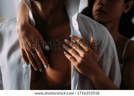 Cropped view of woman hugging businessman from behind in bedroom