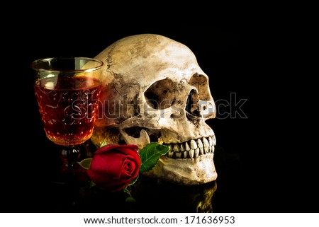 Still life with human skull with red rose bud and vintage glass of wine, reflect on black background
