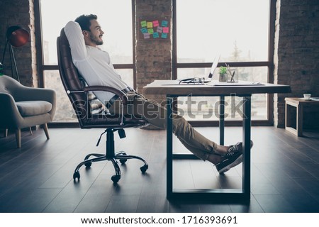 Profile side view of his he nice attractive chic elegant confident cheerful man qualified expert shark sitting in chair having rest at modern loft brick industrial style interior workplace station Royalty-Free Stock Photo #1716393691