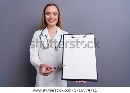 Portrait of nice attractive content cheerful blonde girl doc qualified therapist showing medical form signing contract service medicare isolated over grey violet pastel color background
