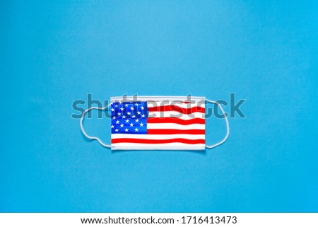 The concept of protection. Medical mask on the face, in the form of the flag of USA on a blue background on top. Surgical masks rubber ear straps. A typical 3-layer surgical mask.