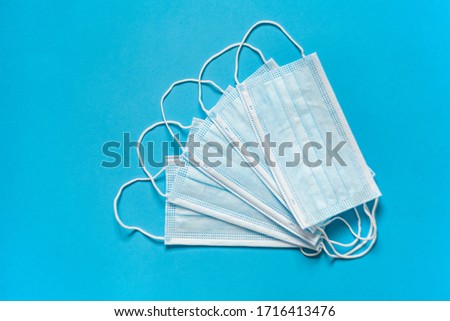 The concept of protection. Medical mask on the face, on a blue background on top. A typical 3-layer surgical mask to cover the mouth and nose. The procedure of the mask against bacteria.