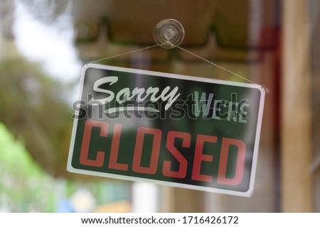 Close-up on an closed sign in the window of a shop saying "Sorry, we're closed".