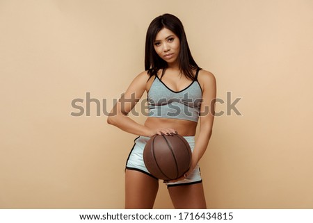 Beautiful african american sportswoman holding ball and looking at camera isolated on beige