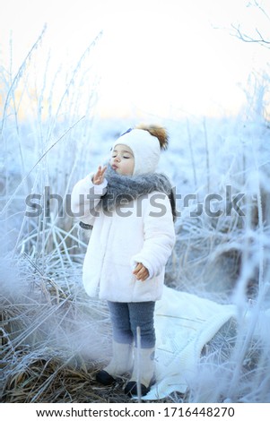 little girl in white jacket in winter fairy tail warm her fingers