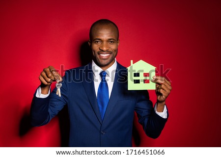 Photo of handsome dark skin business guy hold key chain green paper house real estate agent broker offer sale price wear blue formalwear suit tuxedo isolated red burgundy background