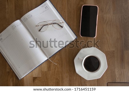  office table desk. Workspace with diary, mobile, 
glasses and smartphone and other supplies with cup of coffe on wood background. Flat lay, top view