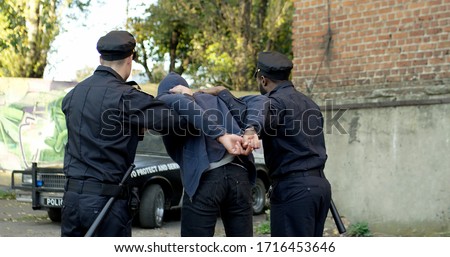 Two Police Officer Arresting Young Man. Police enforcement concept. Royalty-Free Stock Photo #1716453646