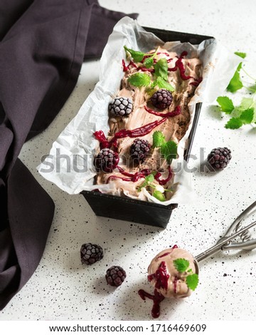 Berry ice cream with chocolate. Blackberries and mint. Summer dessert on a white table.