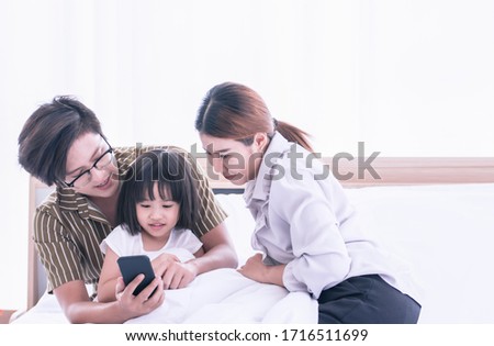 Asian parents helping their daughter to learn online at home via mobile phone