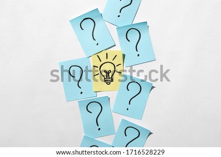 Stickers with question marks and a single light bulb as a sign of a good idea. Concept of business, management, markets, creativity.