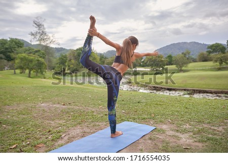    young and beautiful girl doing yoga on rugs in nature                            