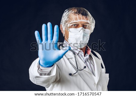 Male Doctor Showing Stop Sign. Doctor Wearing Medical Mask and Gloves. Close up.