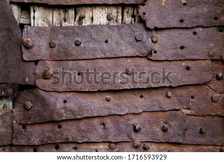 Old rusty strips of iron with weathered corroded surface nailed or riveted to a wooden frame in a close full frame background texture