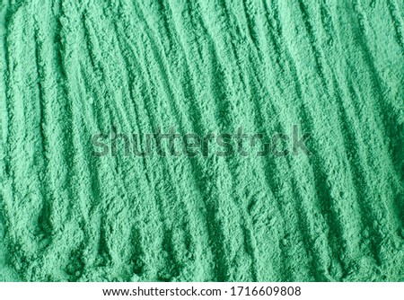 Green cosmetic clay powder (alginate facial mask, spirulina body wrap) texture close up, selective focus. Abstract background. 