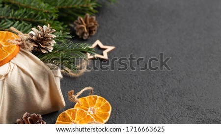 Zero waste christmas concept. Packed in natural fabric gifts and decorations from natural materials on black table, top view, copy space