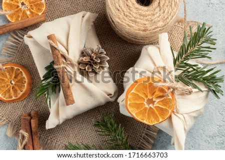 Zero waste christmas concept. Packed in natural fabric gifts and decorations from natural materials on gray table, closeup, top view