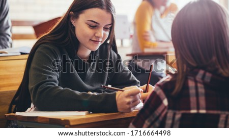 Girls sitting at desk in classroom. Female students studying together in high school.