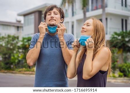 Quarantine is over concept. Man and woman taking off mask against the background of small town houses. We are safe. Coronavirus ended. We won. No more quarantine. Breathe deep. Take off the mask Royalty-Free Stock Photo #1716695914