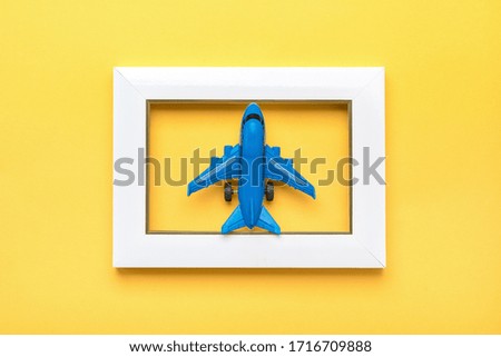 blue plane in white photo frame isolated on yellow background Flat lay Top view Summer, travel, vacation concept Holiday card