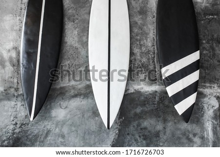 Black and white color surf board on gray concrete wall background. Contemporary interior design of cafe in minimalist style. Dark shabby texture.