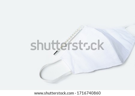 White cotton fabric face mask, personal protective equipment to protect from Covid19 with mercury thermometer. Flat lay, health and medical concept Royalty-Free Stock Photo #1716740860